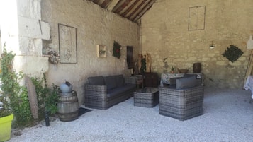 Un intérieur rustique avec des meubles en osier, un mur en pierre et un plafond avec des poutres en bois.
