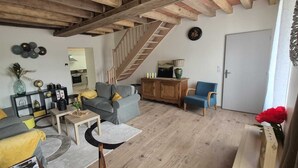 A living room with a sofa, armchairs, a coffee table, a cabinet, a staircase, and a door. - Large gite for up to 8 people, close to Beauval and the Loire castles (Mareuil-sur-Cher)