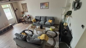 A living room with a grey sofa, a coffee table, and a small side table. There is a window with curtains, a map on the wall, and a plant on the side table. - Large gite for up to 8 people, close to Beauval and the Loire castles (Mareuil-sur-Cher)