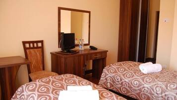 Habitación de hotel con dos camas, un escritorio, una silla, un televisor y un espejo.