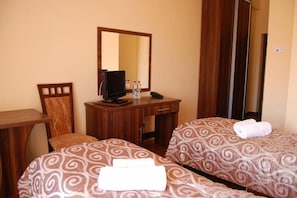 A hotel room with two beds, a desk, a chair, a television, and a mirror. - Solanki Medical Spa (Inowrocław)