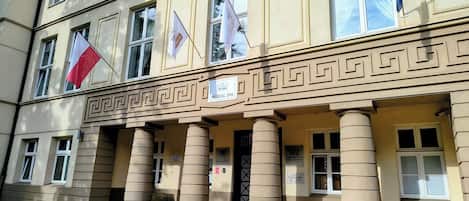 Um edifício com fachada clássica, colunas, placa de spa médico e várias bandeiras.