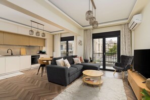 A modern living room with a sofa, coffee table, and TV. - Oak tree: Modern two Bedroom apartment (Thessaloniki)