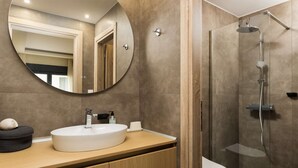 Une salle de bain moderne avec un miroir rond, un lavabo et une douche.