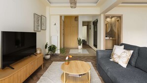 Un salon avec un téléviseur, un canapé et une table basse en bois.