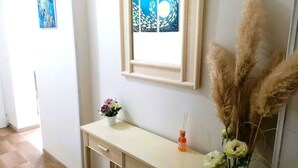 A room with a desk, a framed artwork, a vase with flowers, and tall decorative plants. - Apartment Gioia: comfort and relaxation just minutes from Maria Cecilia Hospital (Lugo)