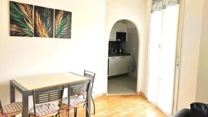 A dining area with a table and chairs, a kitchen visible through an archway, and a black leather sofa. - Apartment Gioia: comfort and relaxation just minutes from Maria Cecilia Hospital (Lugo)