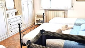 A bedroom with two beds, a dresser, and a radiator. - Apartment Gioia: comfort and relaxation just minutes from Maria Cecilia Hospital (Lugo)