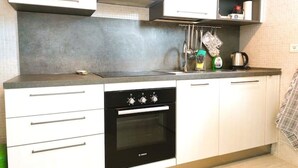 A kitchen with a Bosch oven, white cabinets, a countertop, and a hanging rack with kitchen items. - Apartment Gioia: comfort and relaxation just minutes from Maria Cecilia Hospital (Lugo)