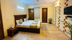 A bedroom with a bed, bedside table, ceiling fan, and a TV on the wall. - Fortune Home Service Apartment 4Bhk D-36 (New Delhi)