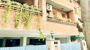 A multi-story building with a balcony, air conditioning units, and a tree in the foreground. - Fortune Home Service Apartment 4Bhk D-36 (New Delhi)