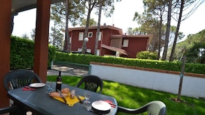 Una mesa para comer al aire libre con sillas, una botella y un plato de comida.