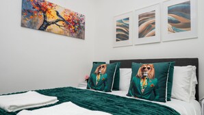 A hotel room with a bed, pillows, a blanket, and artwork on the walls. - New Modern Boutique 4BDR Home in Central Brighton (Brighton and Hove)
