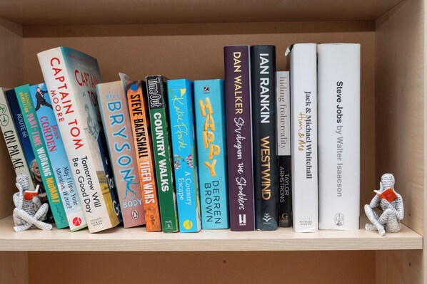 A bookshelf with various books, including titles like 'Captain Tom' and 'The Body.'