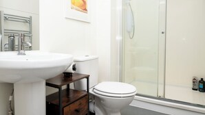 A bathroom with a white sink, toilet, and glass shower enclosure. - New Modern Boutique 4BDR Home in Central Brighton (Brighton and Hove)
