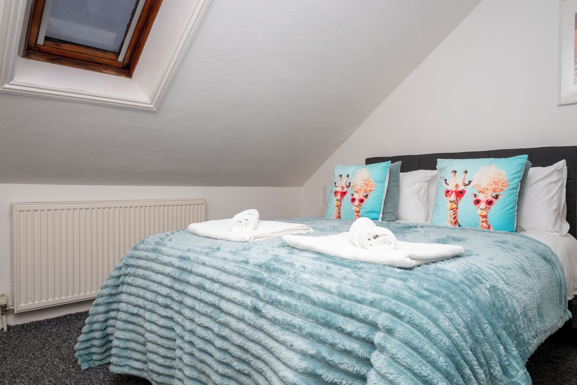 A bedroom with a bed, pillows, a radiator, and a window.