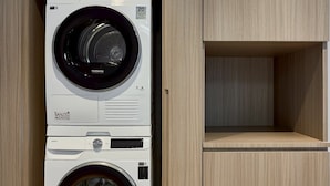 Una unidad de lavadora y secadora Samsung de carga frontal con un gabinete de madera encima.