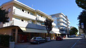 Un hotel de varios pisos con balcones, un estacionamiento y un cielo despejado.