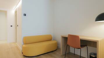 A modern room with a wooden desk, a yellow sofa, and a black chair.