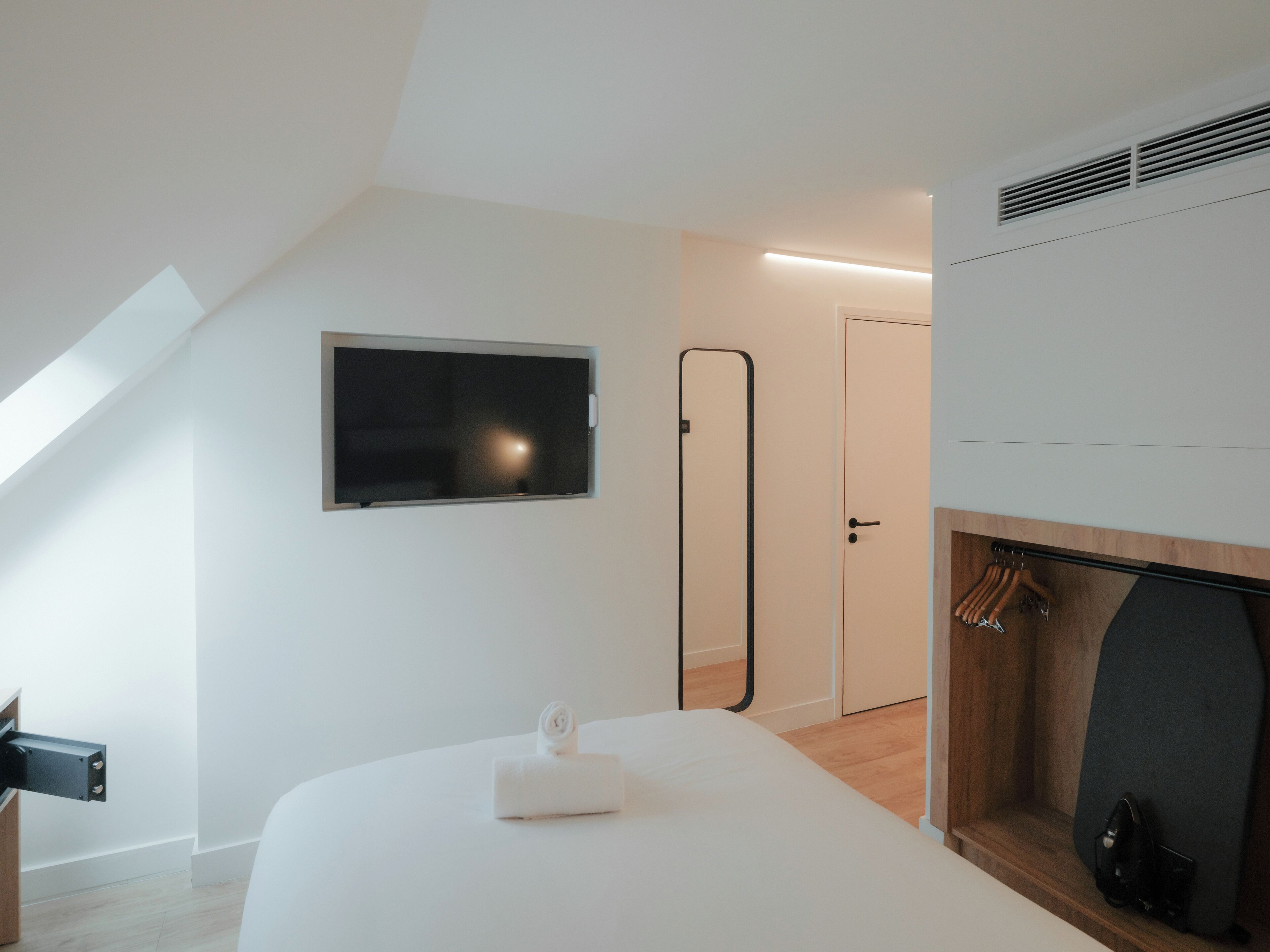 A modern bedroom with a TV, a mirror, a door, and a fireplace.