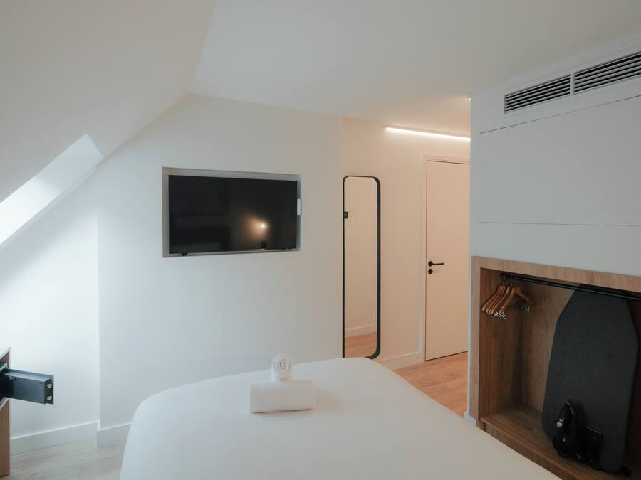 A modern bedroom with a TV, a mirror, a door, and a fireplace.
