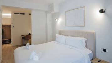 A hotel room with a large bed, a bedside table, a wall-mounted light, and a framed artwork.