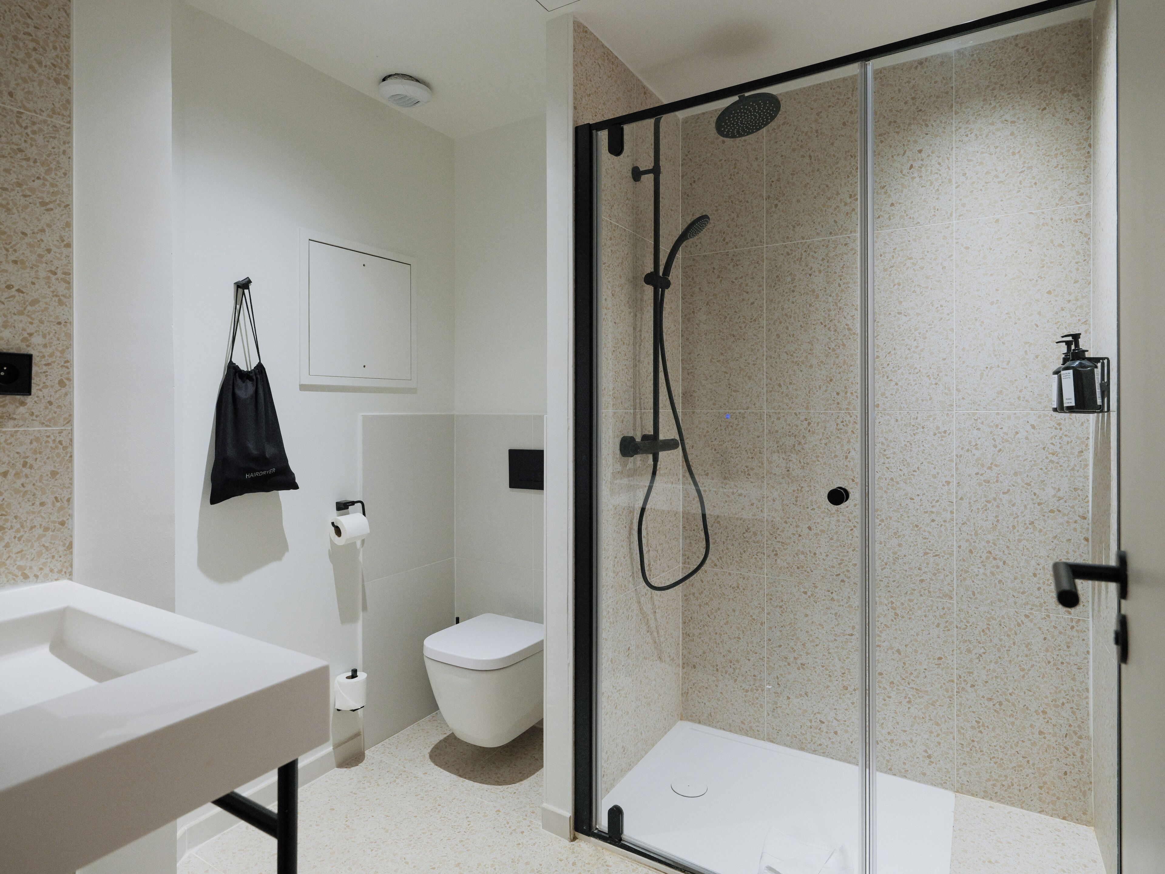 A modern bathroom with a glass-enclosed shower, a toilet, and a sink.