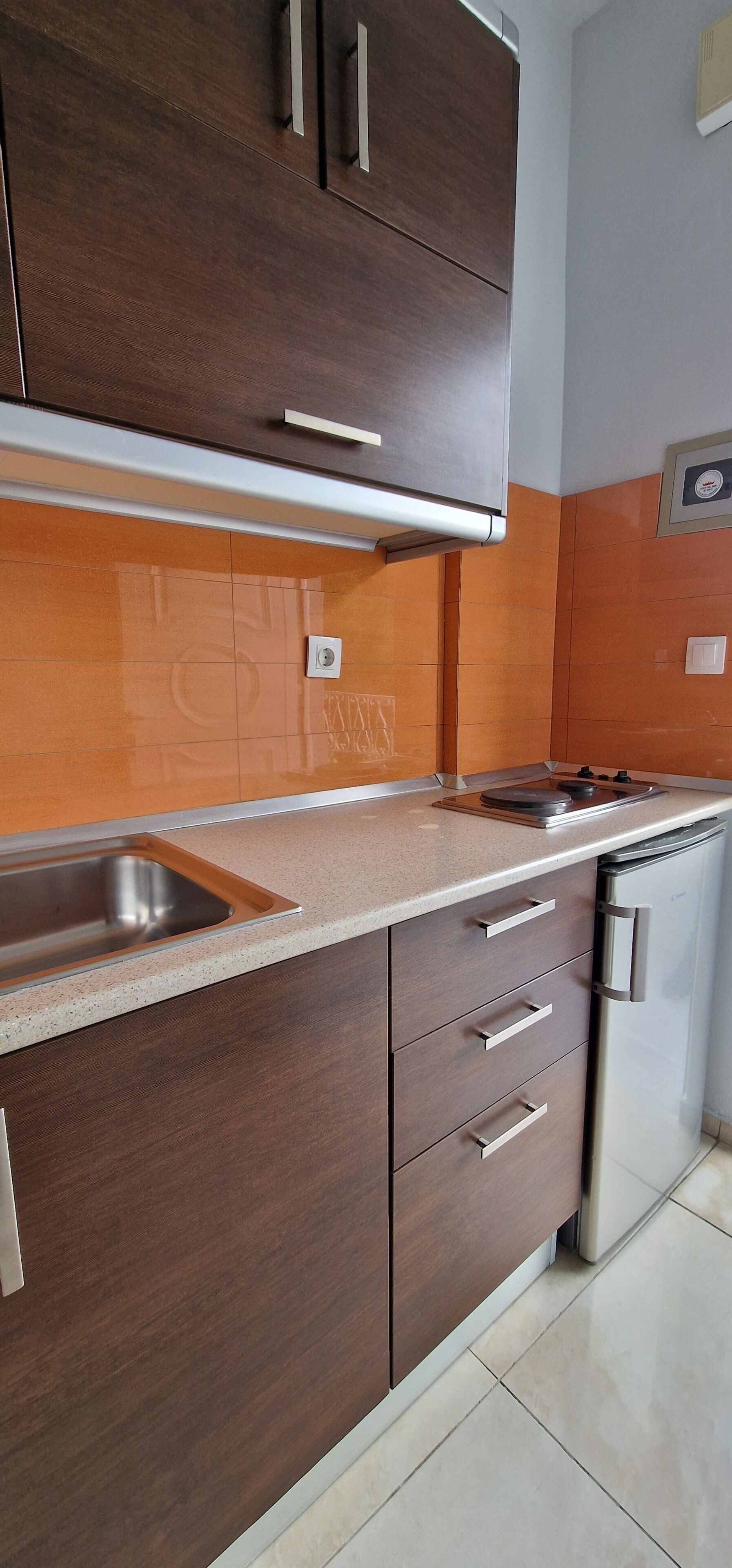 A kitchen with dark wooden cabinets, a stainless steel sink, and a built-in oven.