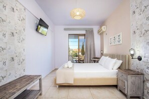 A bedroom with a bed, a bedside table, a lamp, a radiator, and a TV on the wall. - PAGONA STUDIO (Rhodes)