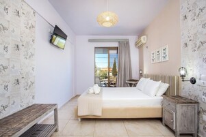 A bedroom with a bed, a bedside table, a lamp, a radiator, and a TV on the wall.