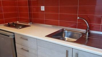A kitchen with light wood cabinets, a stainless steel sink, and a dishwasher.