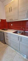 A kitchen with light wood cabinets, a stainless steel sink, and a dishwasher.