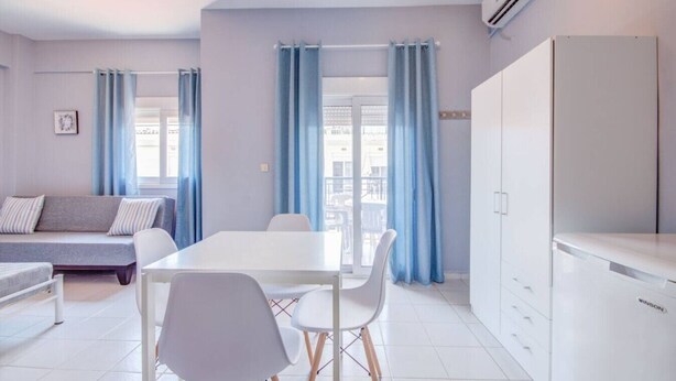 Een moderne kamer met een bank, eettafel, stoelen en een kledingkast.