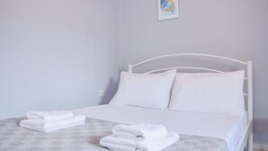 Een wit bed met twee kussens, een wit hoofdeinde en een ingelijste foto aan de muur.