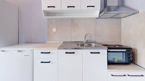 Een compacte keuken met een ingebouwde oven, een magnetron en een spoelbak.