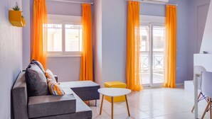 Een moderne woonkamer met een bank, een bijzettafeltje en uitzicht op een balkon.