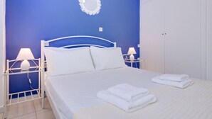 Een slaapkamer met een bed, twee nachtkastjes met lampen, een spiegel aan de muur en een kledingkast.