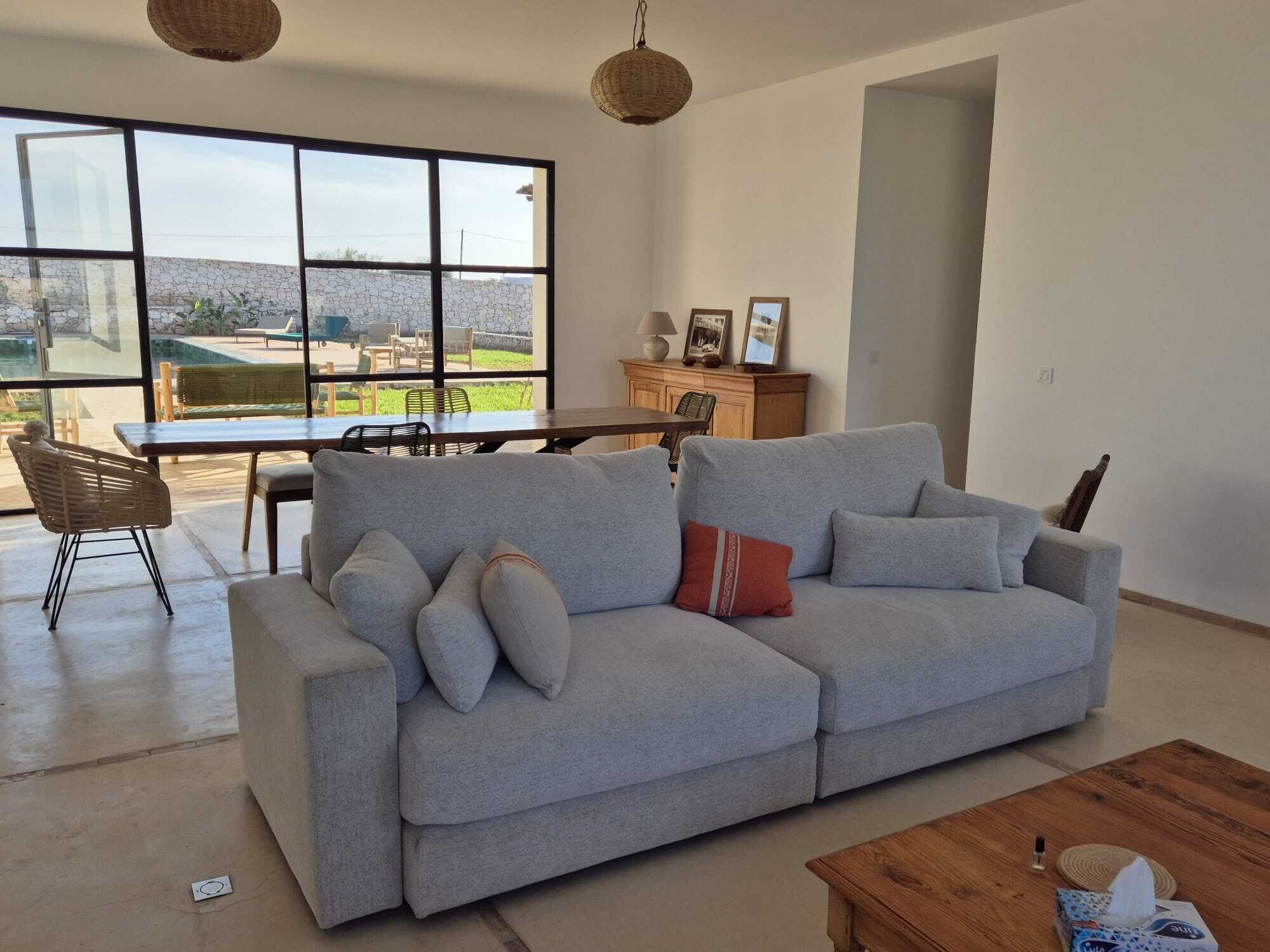 A living room with a grey sofa, a wooden coffee table, and a dining area with a table and chairs.