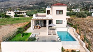 Una moderna casa con piscina, un patio con mobili da esterno e vista sulle montagne.