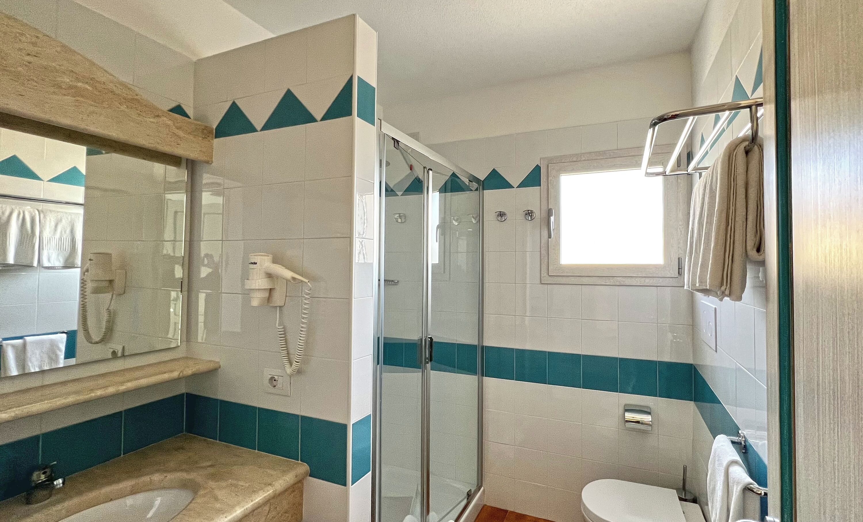 Ein Badezimmer mit Duschkabine, Toilette, Waschbecken und Spiegel.