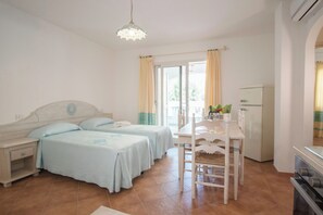 Ein Schlafzimmer mit zwei Betten, einem Esstisch und einer Küchenzeile.