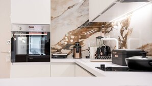 Eine moderne Küche mit Einbauofen, Kaffeemaschine und Marmorfliesenspiegel.
