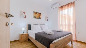 Quarto com cama de madeira, mesa de cabeceira com abajur e obras de arte nas paredes.