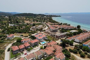 Vista aérea de una zona residencial costera con casas, piscina y playa.