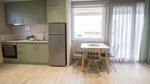 Eine kompakte Küche mit Einbauofen, Kühlschrank und einer Essecke mit Tisch und Stühlen.
