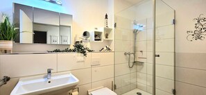 Een moderne badkamer met een wastafel, spiegel, douche en decoratieve accessoires.