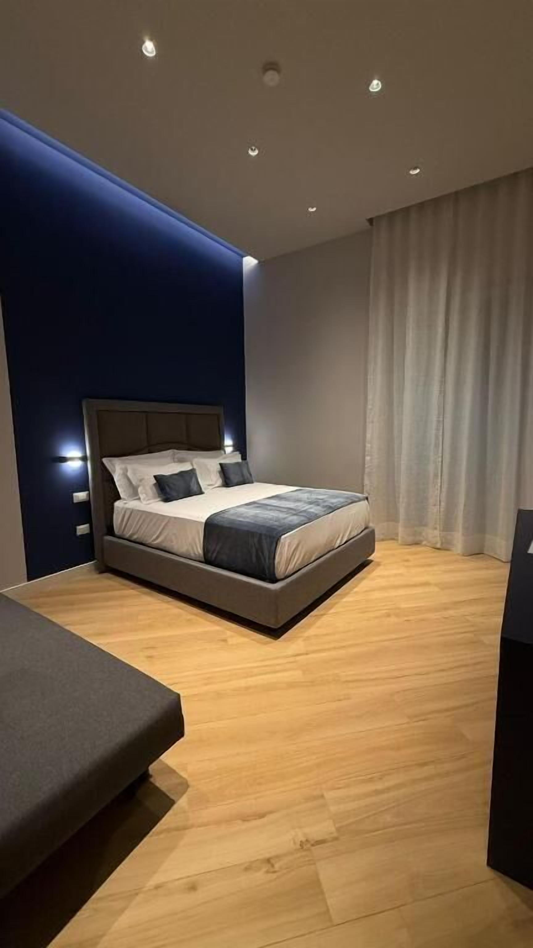A modern bedroom with a bed, bedside tables, and a wooden floor.