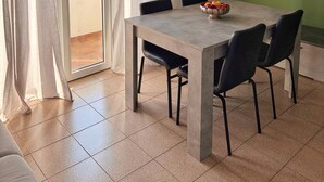 A dining area with a table, chairs, a bowl of fruit, a green wall, and a sliding glass door. - Strategic two-room apartment: M2 Metro, Navigli and Forum (Milano)