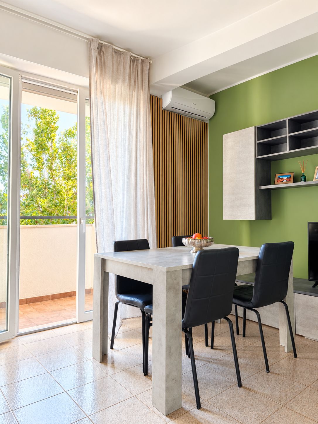 A dining area with a table, chairs, and a view of greenery outside.