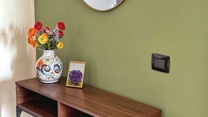 A wooden console table with a mirror above it, a vase with flowers, and a framed picture on the table. - Strategic two-room apartment: M2 Metro, Navigli and Forum (Milano)
